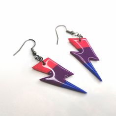 two pairs of earrings with purple, red and blue designs hanging from silver earwires