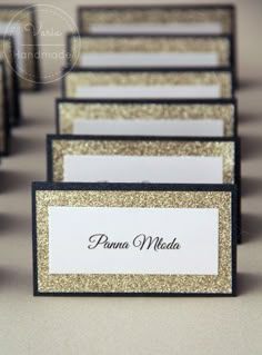 place cards are lined up in rows on a table with gold glitter and black border