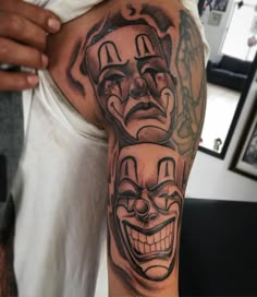 a man with a tattoo on his arm has two clown faces and is wearing a white t - shirt