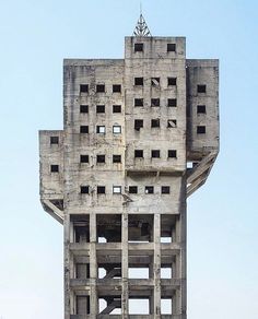 a tall building with multiple windows on the top and bottom floors that are made out of concrete