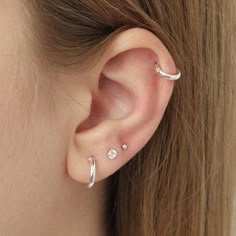 a woman's ear is shown with two piercings on the top of it