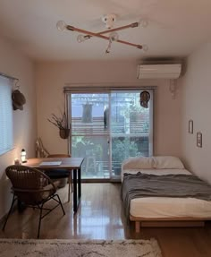 a small bedroom with a bed, desk and chair in front of a sliding glass door