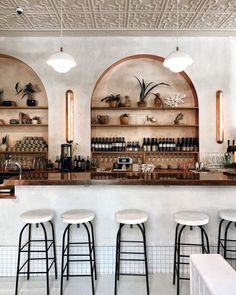 the bar has several stools and shelves with bottles on them in front of it