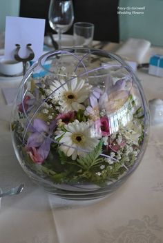 a vase filled with lots of flowers on top of a white tablecloth covered table