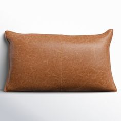 a brown leather pillow sitting on top of a white wall