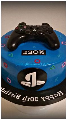 a blue birthday cake with a video game controller on it's top and name