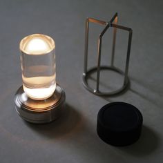 a small light sitting on top of a table next to a metal holder with a candle in it