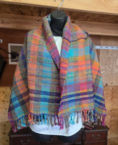 a multicolored shawl hanging on a coat rack