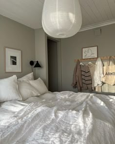 a bed with white linens and pillows in a bedroom next to two pictures on the wall