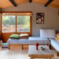 a bedroom with two beds and a table in front of the window that is open