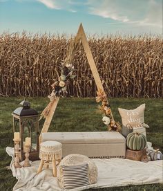 an outdoor ceremony setup in front of a cornfield with candles and decorations on the ground