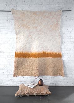 a white brick wall with a tan and brown rug hanging on it's side