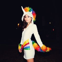 a woman dressed in a white unicorn costume with multi - colored feathers on her head