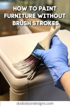 a person in blue gloves is painting furniture with brush strokes on the top of it