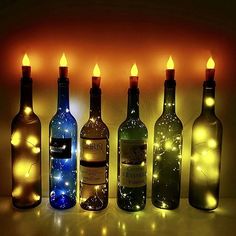 several bottles with lights on them are lined up in front of each other as if for wine tasting