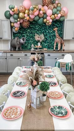 a table set up with plates and place settings for a jungle themed birthday or baby shower