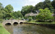 a stone bridge over a river with people walking on it