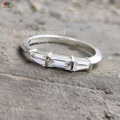 a three stone diamond ring sitting on top of a rock