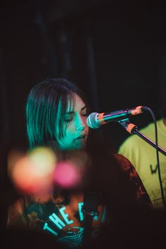 a woman singing into a microphone while standing next to a man