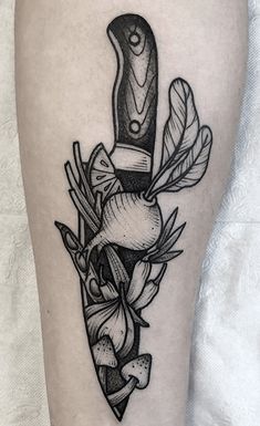 a black and white tattoo on the leg of a person with a knife in it