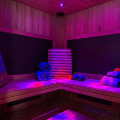 an indoor sauna with purple lighting and towels on the bench in front of it