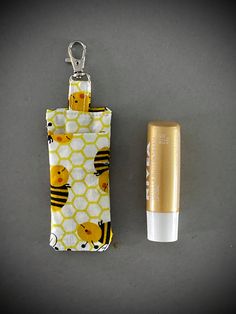 a yellow and white cell phone case next to a small gold lighter on a gray surface