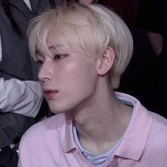 a young man with blonde hair sitting in front of other people at a fashion show