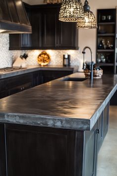 a large kitchen with an island in the middle and lights hanging from it's ceiling