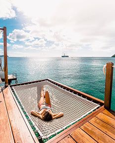 a person laying in a hammock on the deck of a boat looking out to sea