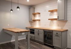 an empty kitchen with gray cabinets and wood counter tops