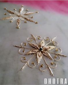 two gold snowflakes sitting on top of a white cloth covered in beading