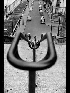 a black and white photo of a street with cars parked on the side of it