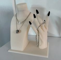 two white mannequins with black nail polishes and chains on their hands