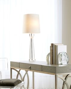 a lamp sitting on top of a table next to a desk with a chair and books