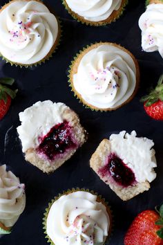 several cupcakes with white frosting and strawberries