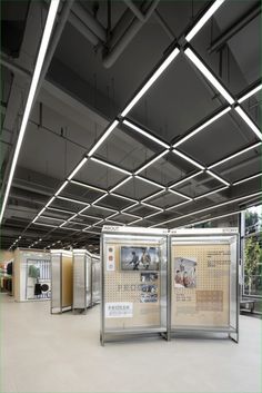 an empty room with several partitions and posters on the walls, in front of trees