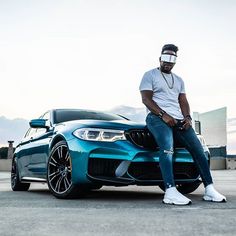 a man sitting on the hood of a blue sports car