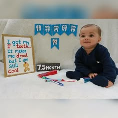 a baby sitting on the floor in front of a birthday sign and toothbrushes