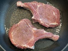 two pieces of raw meat cooking in a frying pan