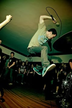 a man is jumping in the air on his skateboard while people watch from behind him