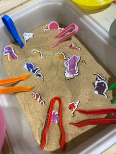 a sand tray with scissors and stickers on it