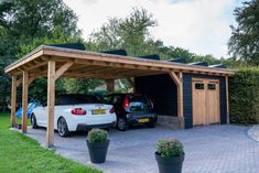 two cars are parked in front of a carport with wooden roof and side walls