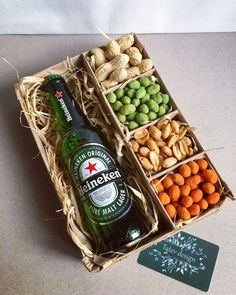 a bottle of beer sitting in a box next to some nuts and other food items