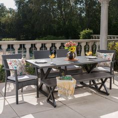 an outdoor table and chairs on a patio with sunflowers in the vase next to it