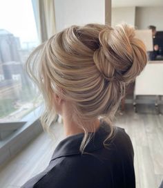 a woman with blonde hair is looking out the window and has her back to the camera