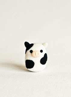 a small black and white cow head sitting on top of a white tablecloth covered surface