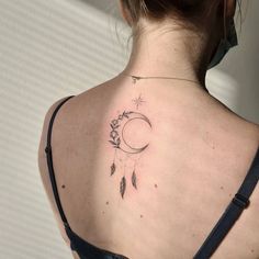 a woman with a tattoo on her back is looking at the moon and stars in the sky