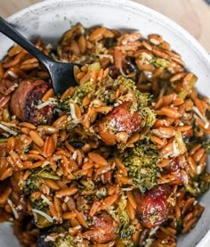 a white bowl filled with broccoli, carrots and other food on top of a wooden table