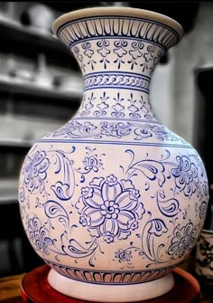 a blue and white vase sitting on top of a wooden table next to a pen holder