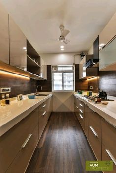 a modern kitchen with wood flooring and white counter tops, along with wooden cabinets